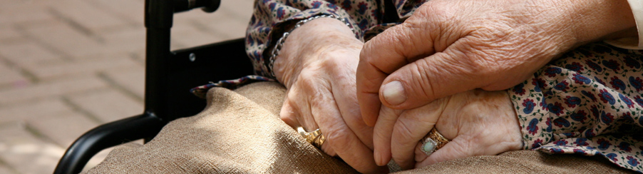 Elderly couple holding hands as woman sits in wheelchair in Seminole, FL