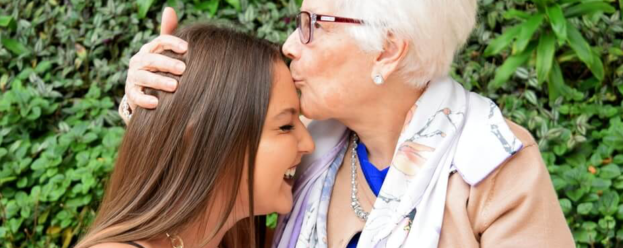 Grandmother hugging and kissing granddaughter's head